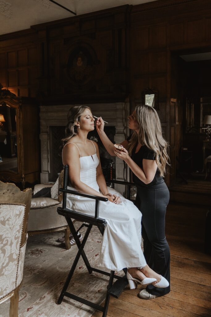 Suffolk wedding photographer having her makeup done in soft morning light at Hengrave Hall bridal suite