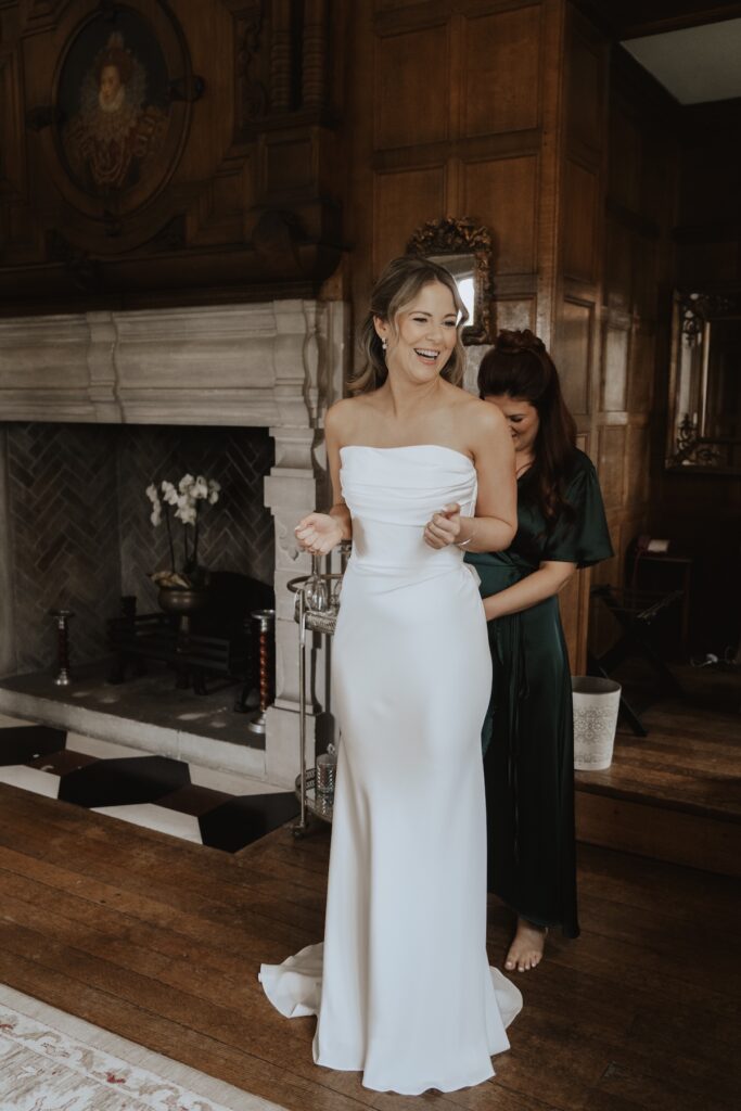 The bride getting her wedding dress on in the bridal suite at Hengrave Hall
