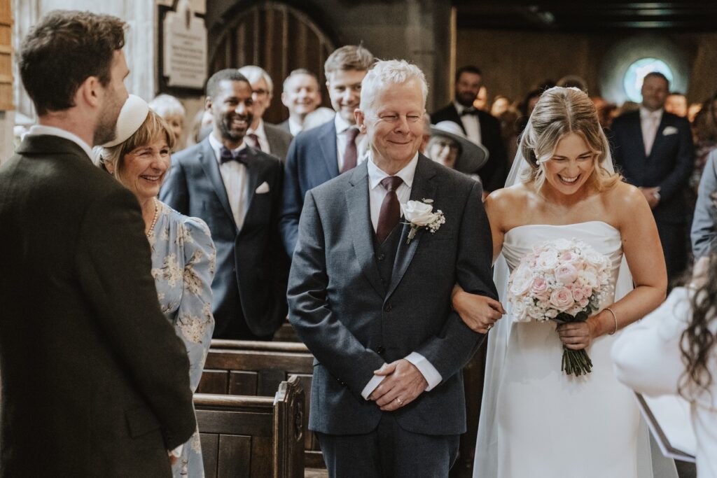 Bride walking down the aisle as the groom watches emotionally
