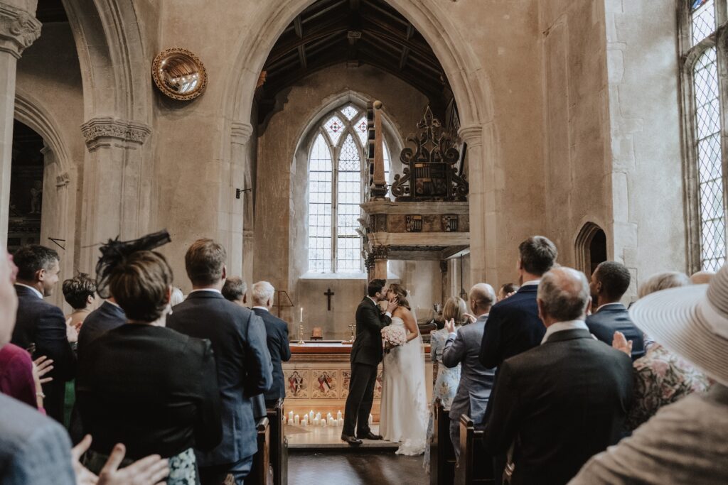 Guests watching the vows in the soft light of the chapel
