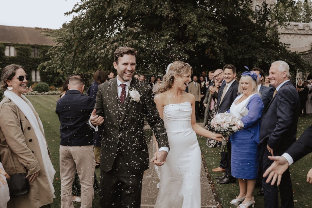 The bride and groom walking through confetti after their Hengrave Hall wedding