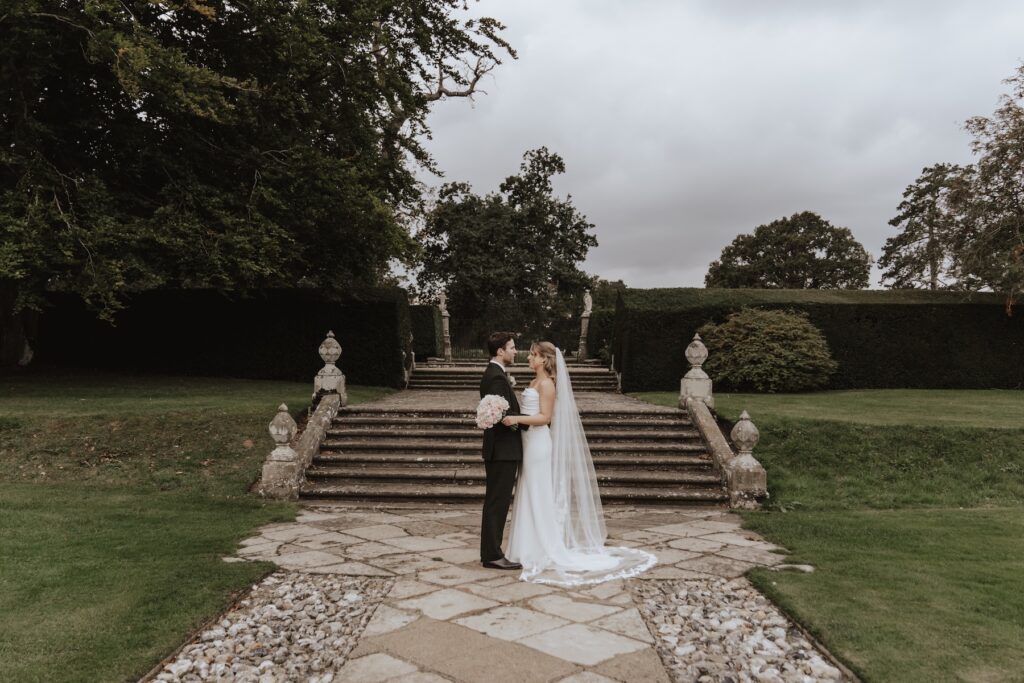 Couple framed by the tall hedges of Hengrave Hall’s gardens