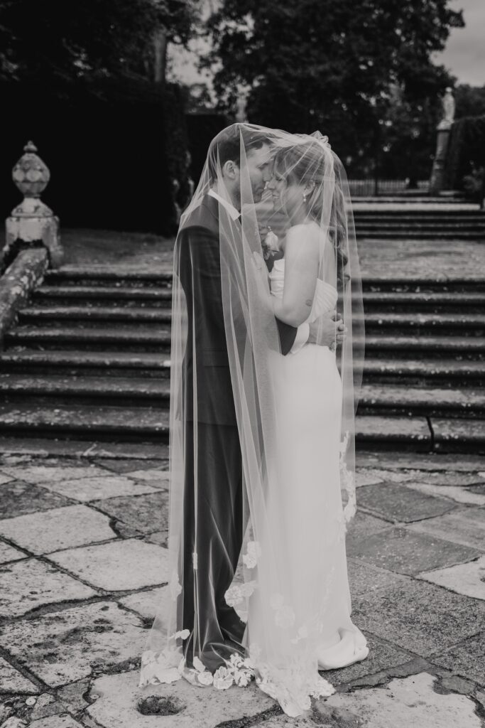 Bride and groom under the veil in the gardens of Hengrave Hall