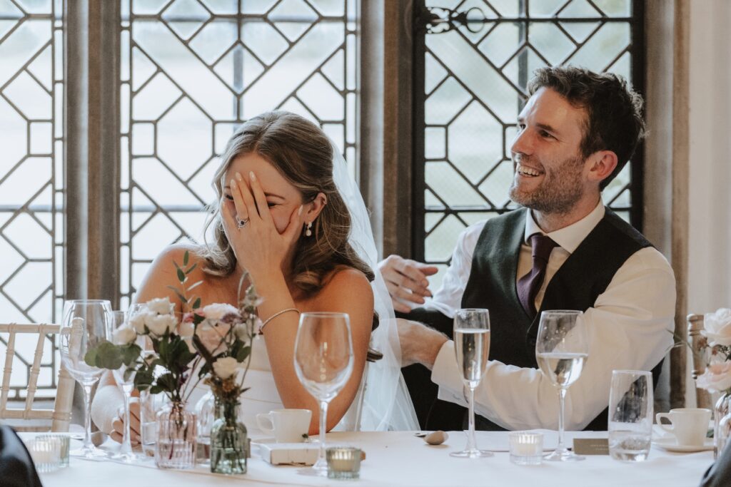 Bride and groom laughing during speeches between courses