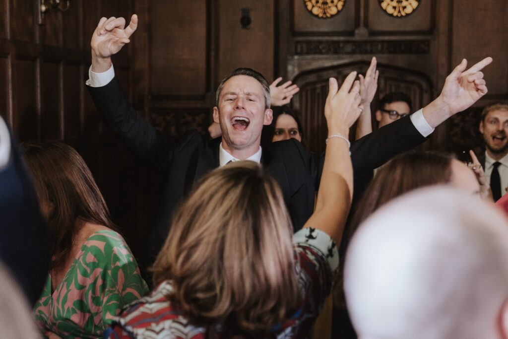 Guests dancing and laughing on the floor under fairy lights at Hengrave Hall