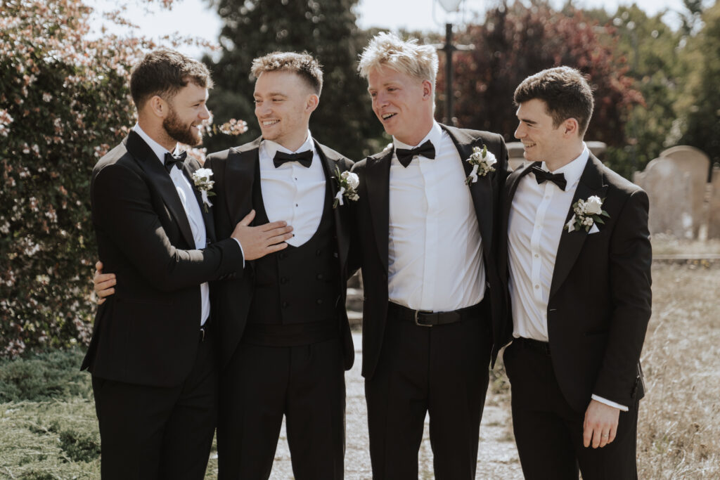 Essex wedding photographer capturing groomsmen outside the church before the wedding ceremony