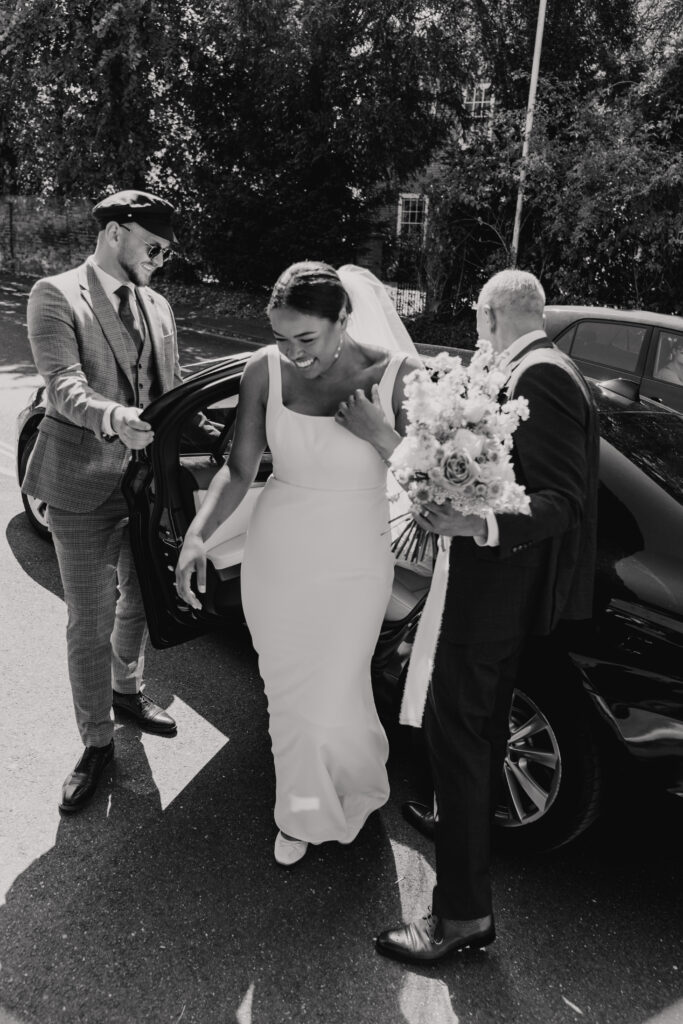 Bride stepping into wedding car in soft morning light