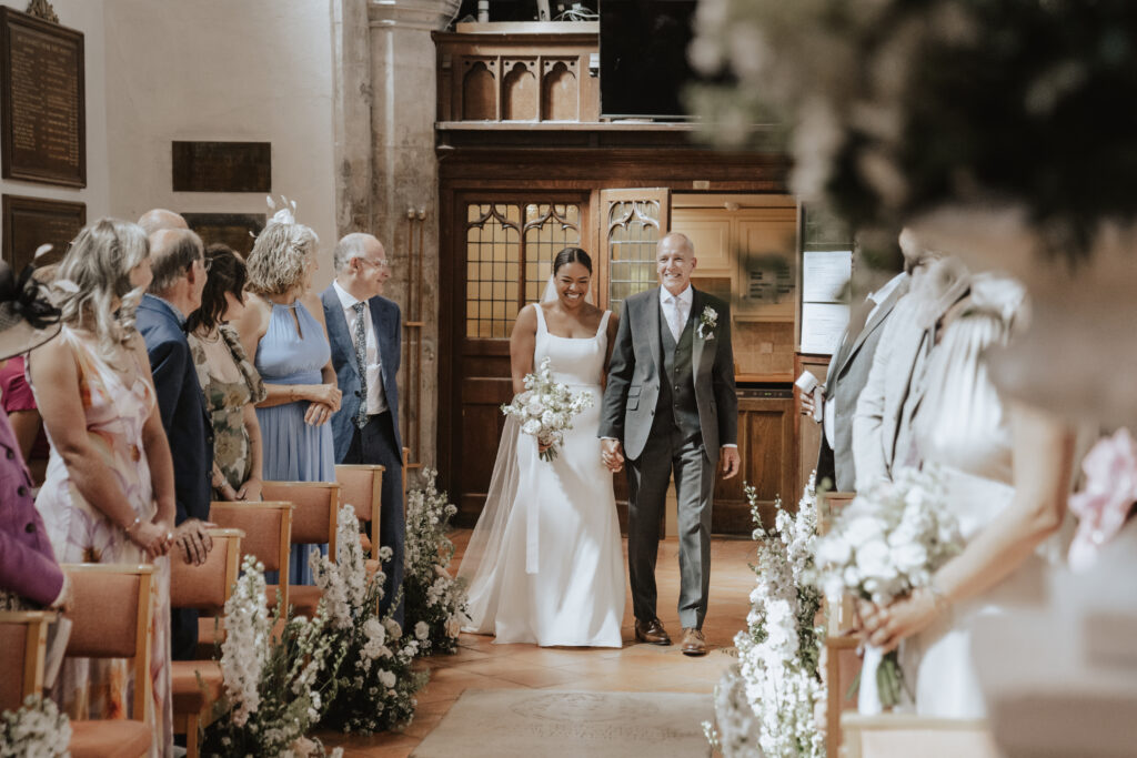 Bride walking down the aisle as with father at Essex church