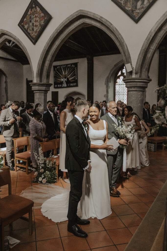 Essex wedding photographer capturing the couple exchanging vows with guests looking on