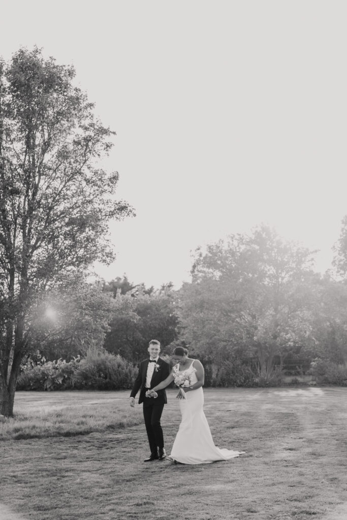 Bride and groom walking hand-in-hand through golden light at High House