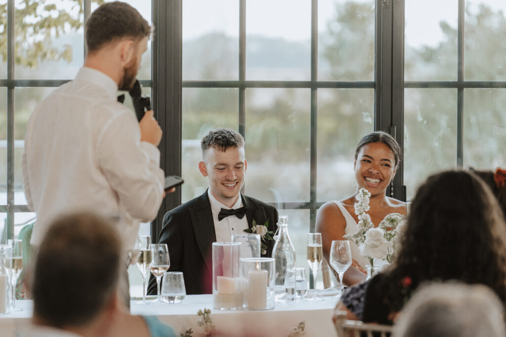 Guests clapping and smiling during the wedding speeches in Essex orangery