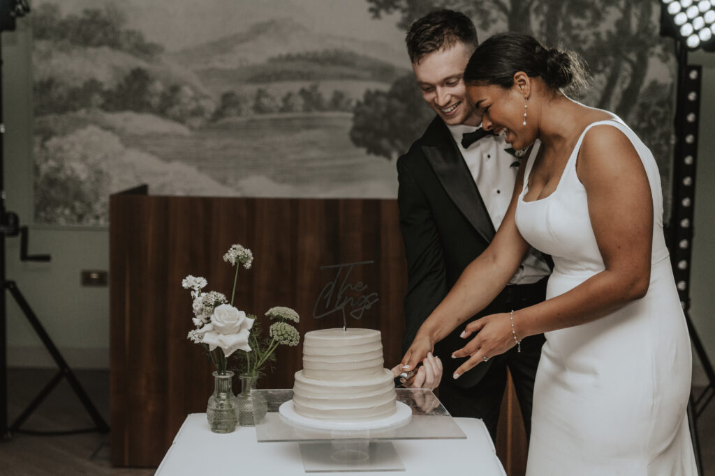 Essex wedding photographer at High House with the couple cutting their wedding cake together