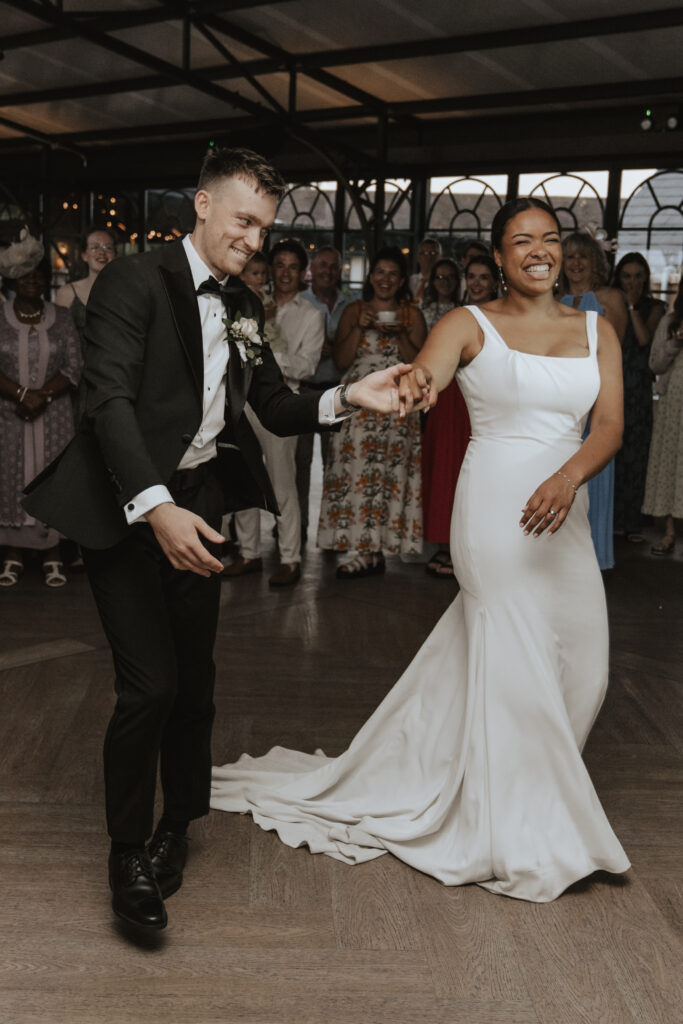 Newlyweds sharing their first dance under fairy lights in the High House orangery