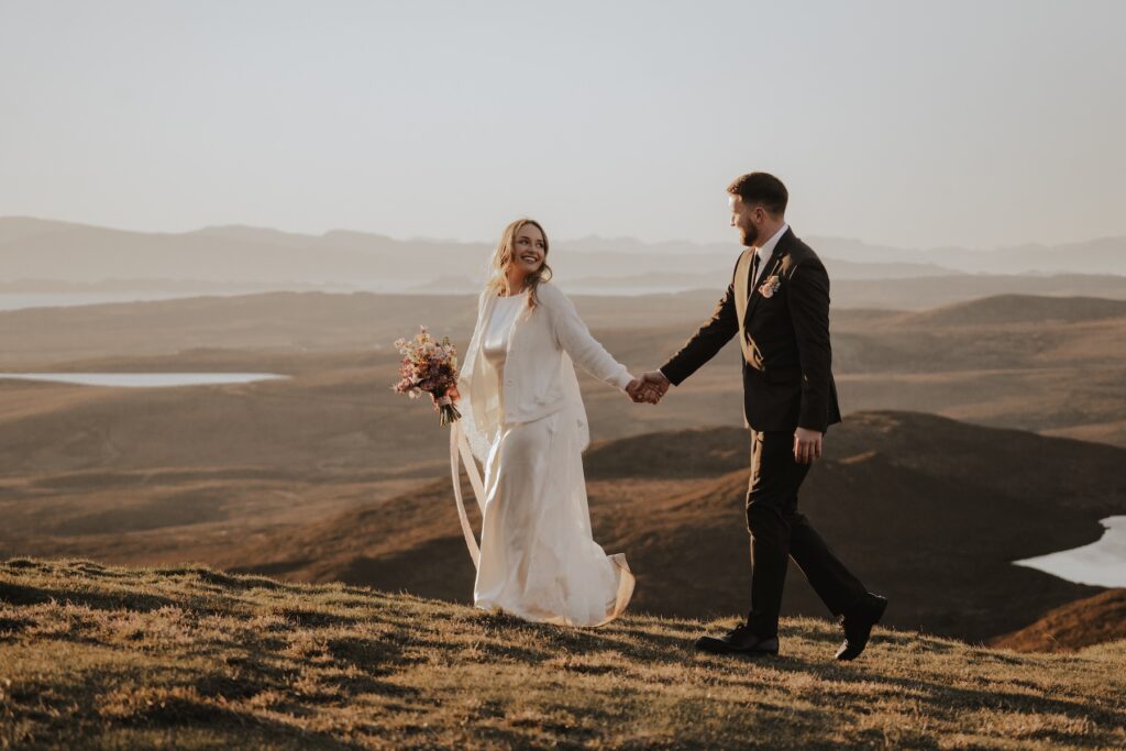 Adventure elopement couple walking hand in hand through Scottish Highlands