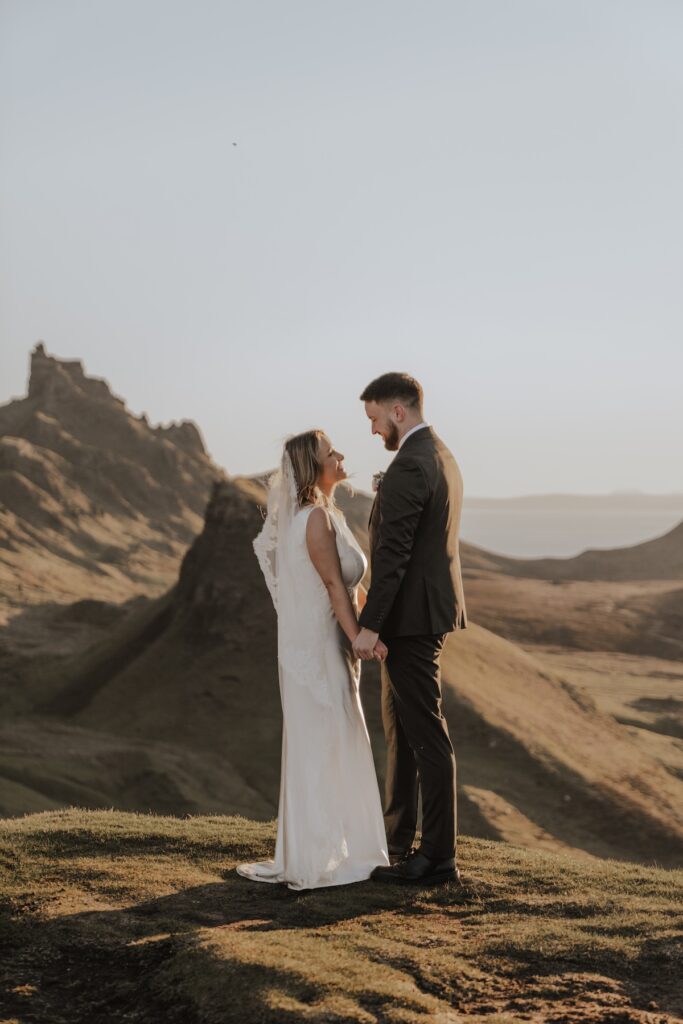 Couple walking hand in hand across dramatic Quiraing landscape in Scotland