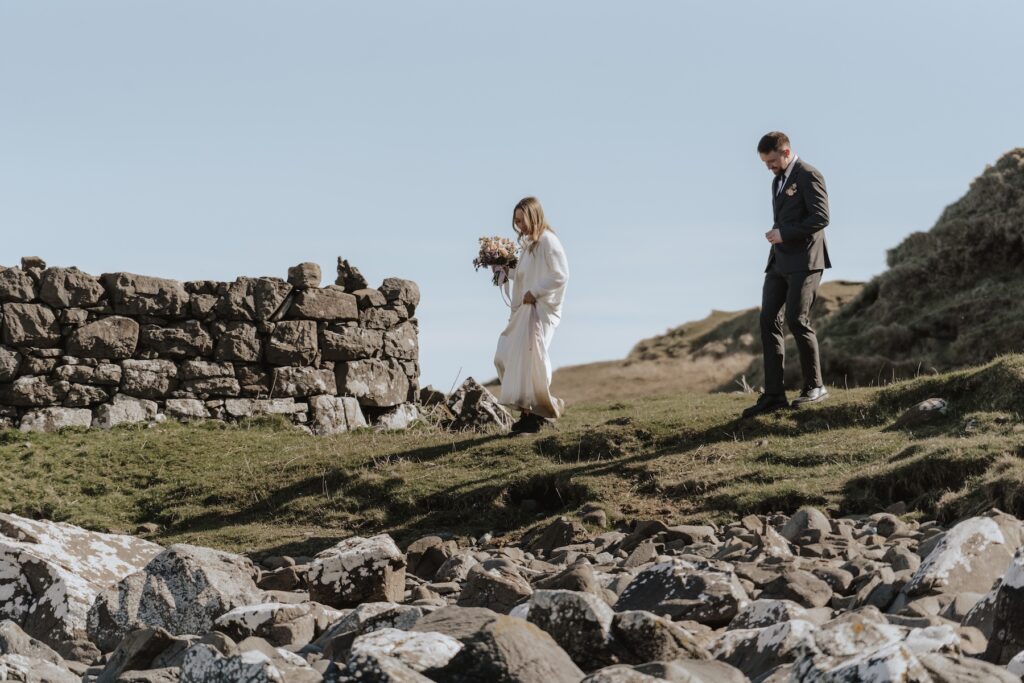 Couple hiking down to Brother’s Point Beach for their Isle of Skye elopement