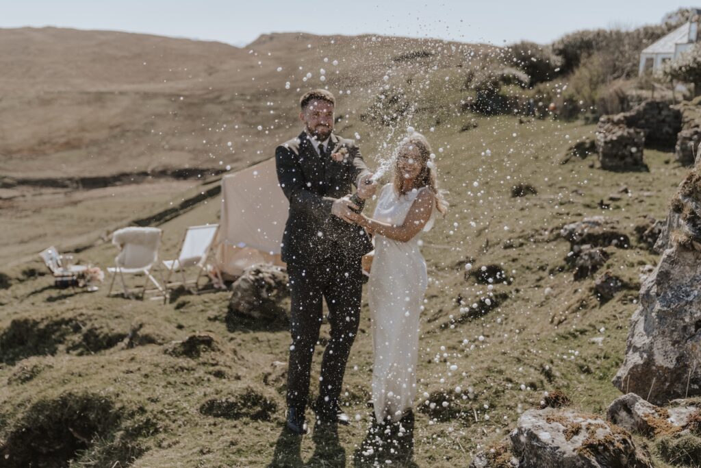 Couple popping champagne on cliff overlooking Brother’s Point at sunset