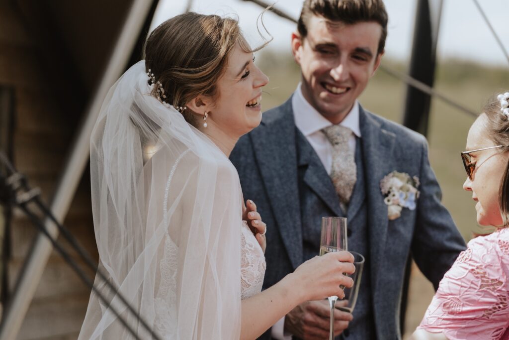 Couple mingling with guests under sunny skies at Jimmy’s Farm, Suffolk