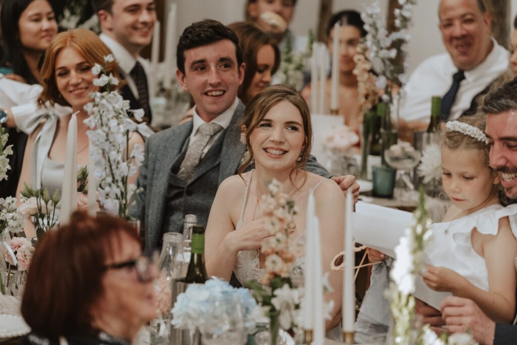 The bride and groom reacting to best man speech at Jimmy's Farm captured by a Suffolk wedding photographer