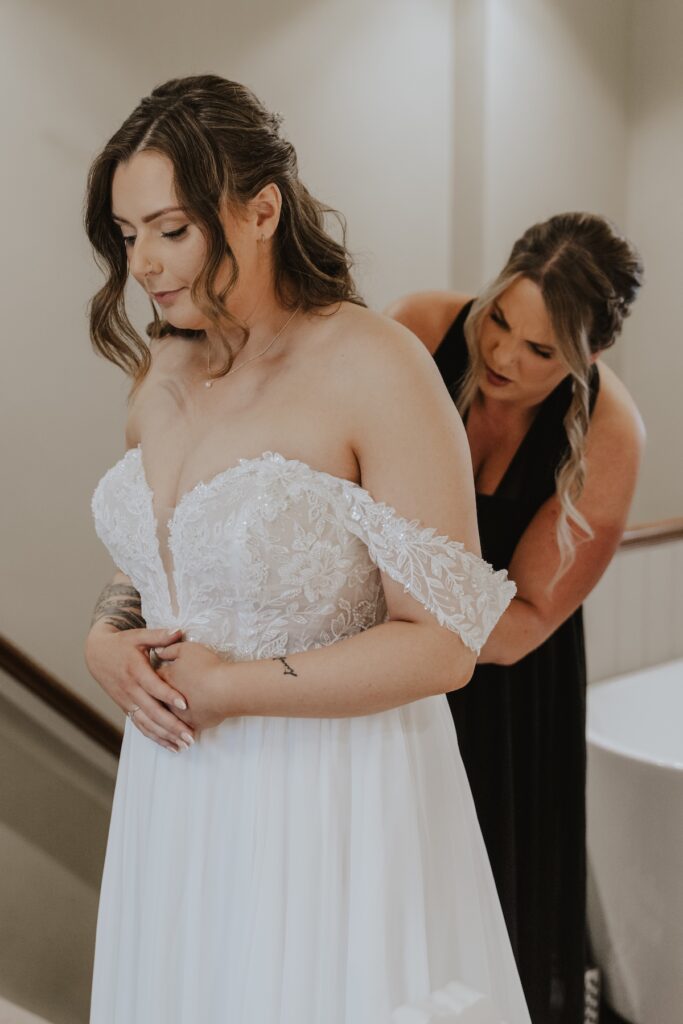 Bridesmaids helping the bride into her elegant wedding gown