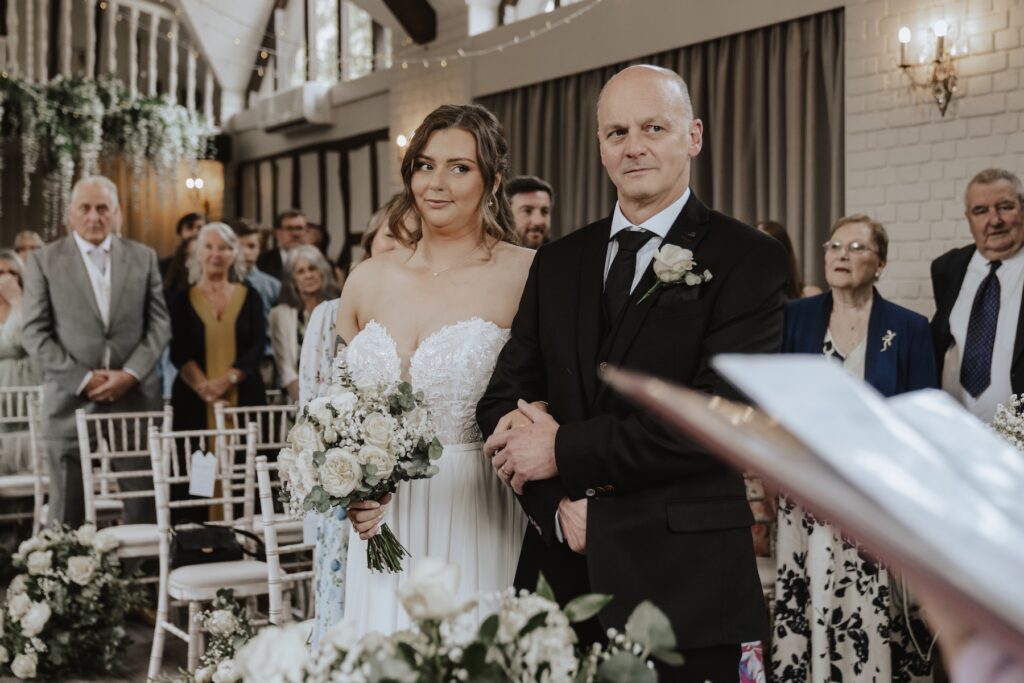 Bride walking down the aisle at Seckford Hall with her dad