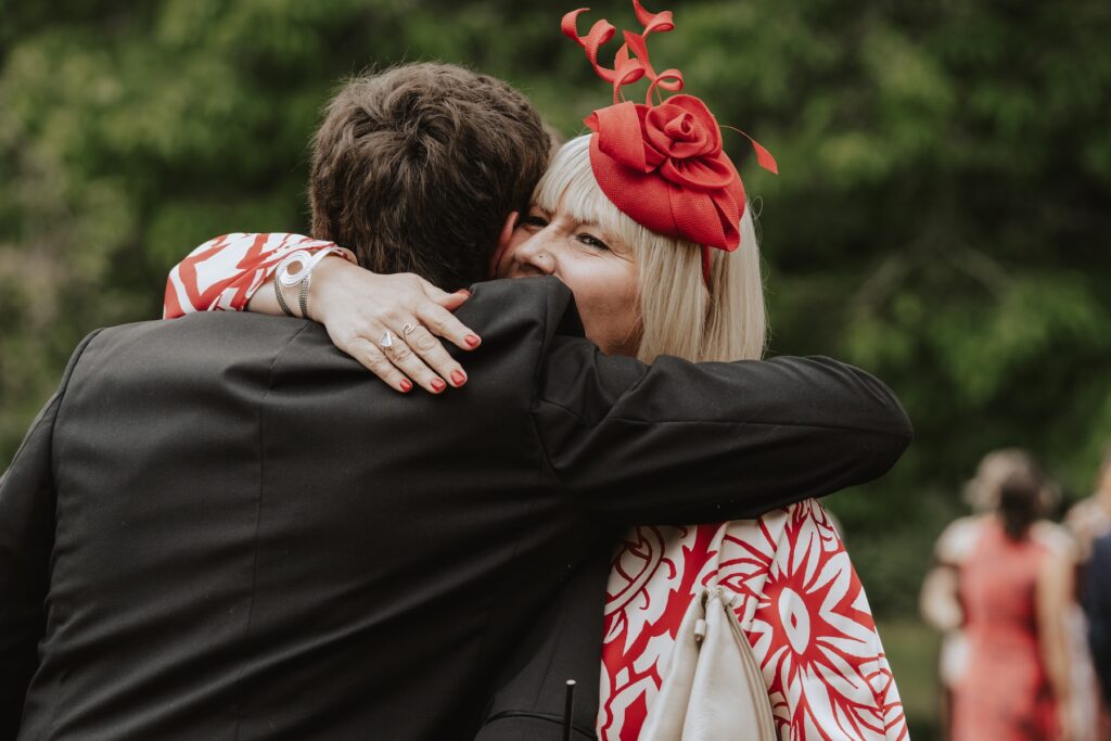 Groom greeting guests with hugs outside the hall