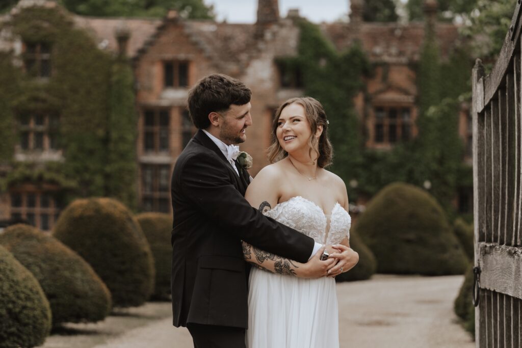 Wide shot of bride and groom in front of the hall’s historic architecture