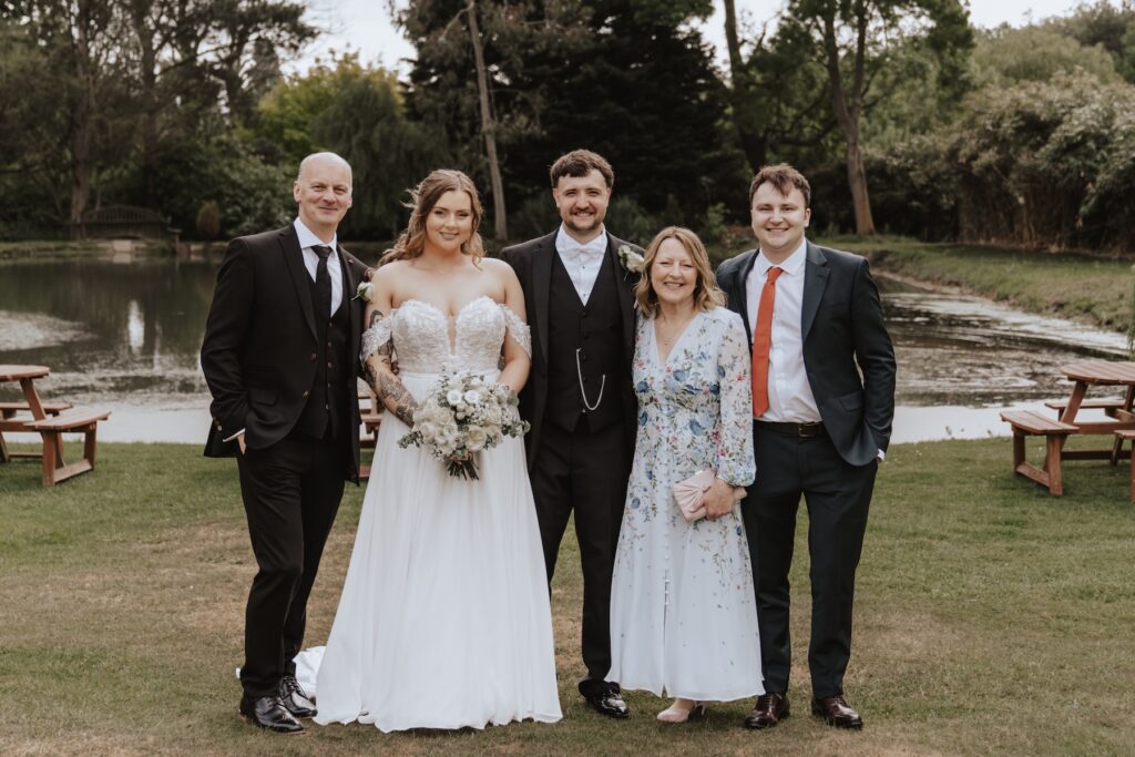 Group photo of family with Seckford Hall’s lake behind them