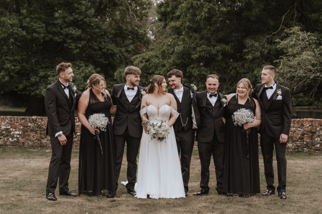 Wedding party laughing together in Seckford Hall’s walled garden
