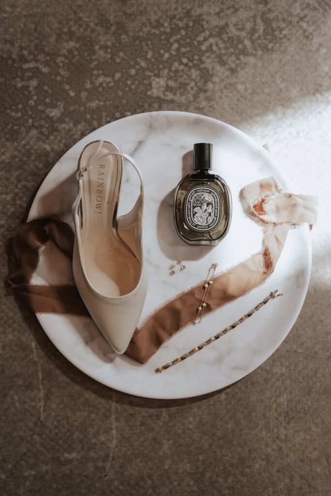 Bride’s wedding shoes and bouquet laid out on a rustic wooden table