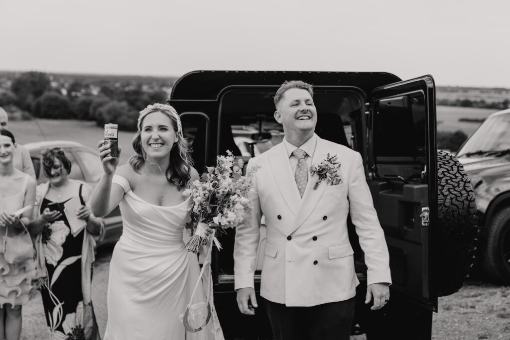 Bride and groom sharing a drink by their 4x4 cooler on the hilltop