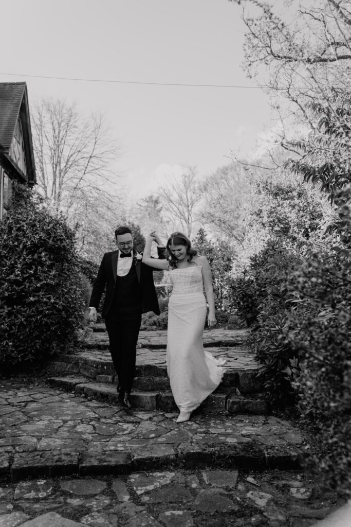 A bride and groom walking down the stairs hand in hand at Hoath House wedding venue in Kent