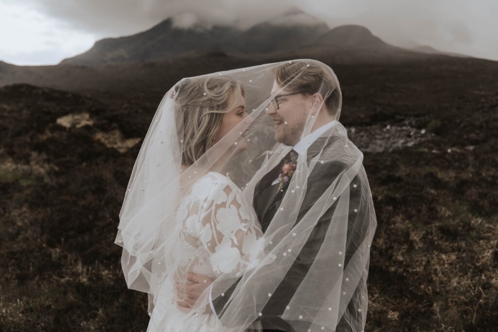 Bride and groom under the veil with the black chilling mountains in the background on the Isle of Skye