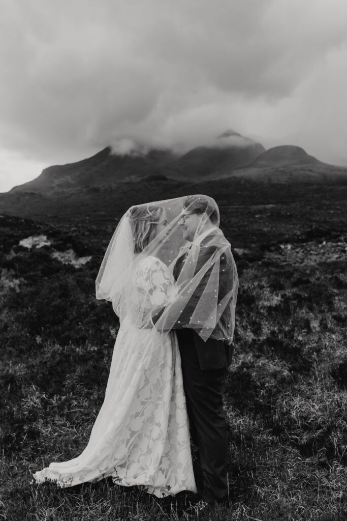 Bride and groom under the veil with the black chilling mountains in the background on the Isle of Skye
