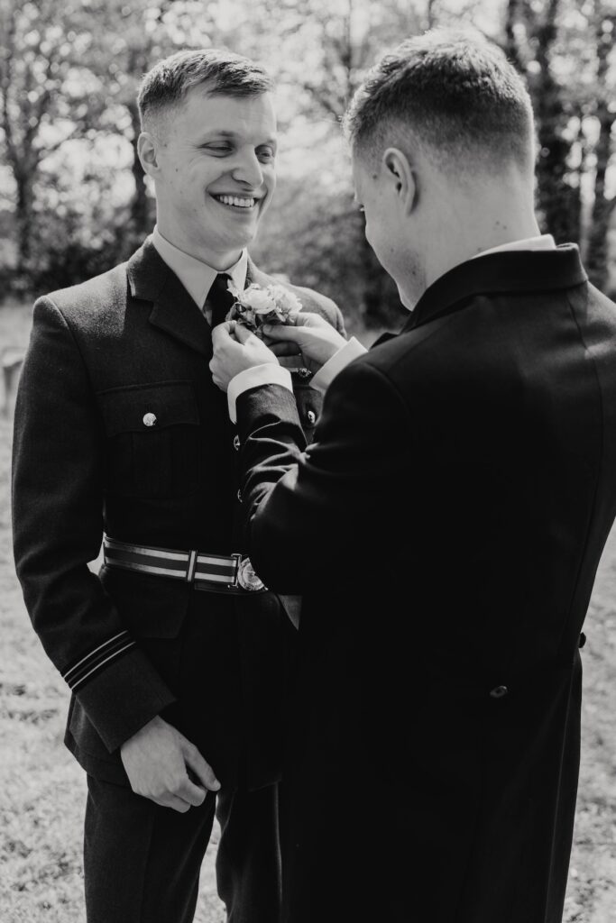 A groom getting his buttonhole put on in Woodbridge outside their church