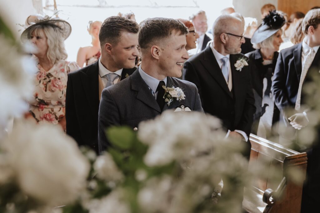 The groom reacting to the bride walking down the aisle at a church ceremony in Suffolk
