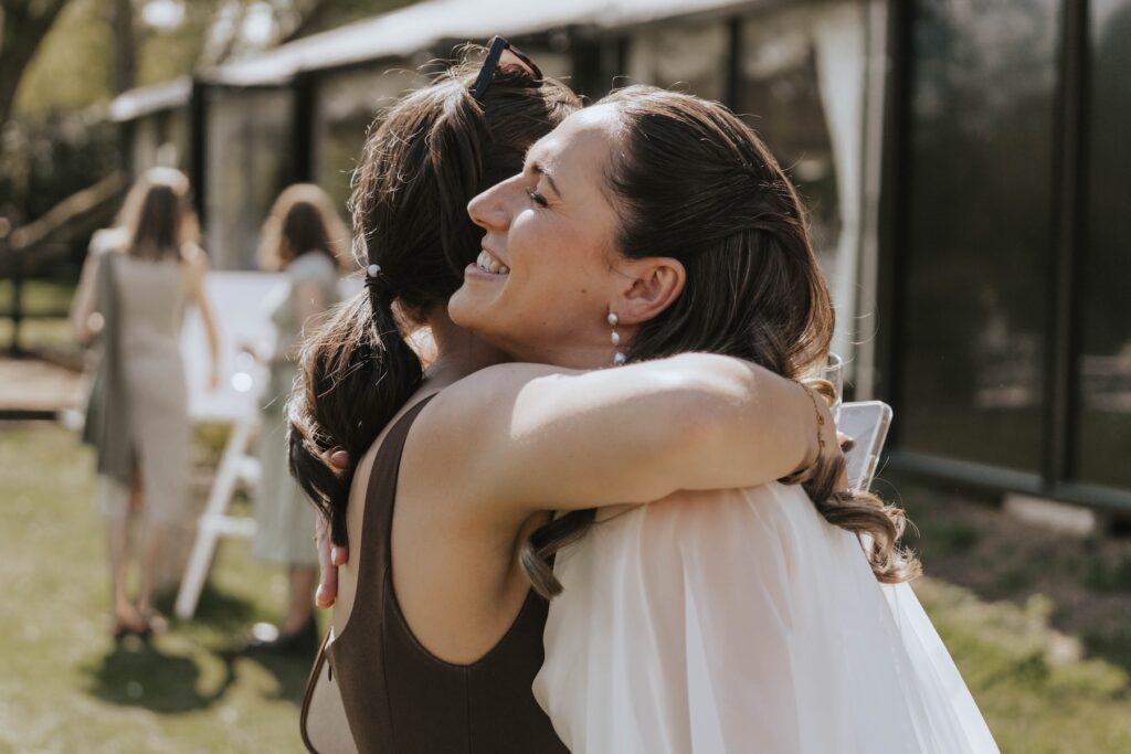 Candid moments of the bride hugging a guest during a wedding drinks reception at Seckford Hall in Suffolk