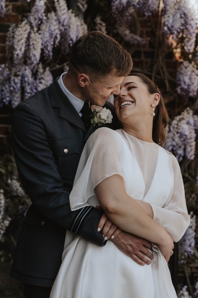Couples portraits taken of a bride and groom on their wedding day outside Seckford Hall with the wisteria in the courtyard