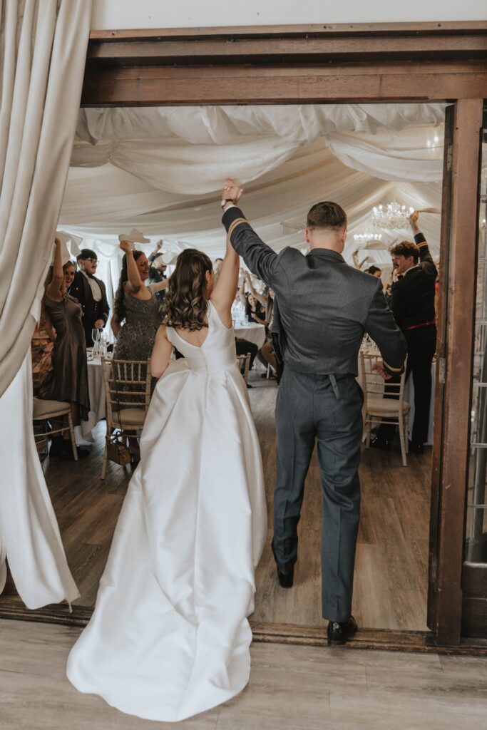 Bride and groom entering wedding reception at Seckford Hall
