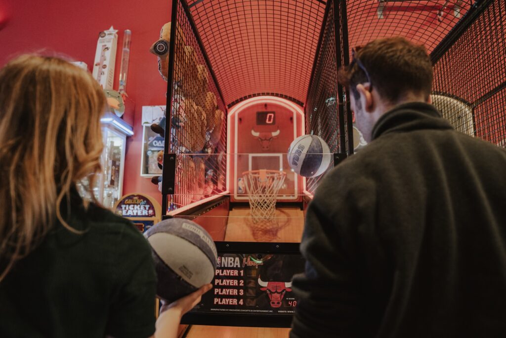 A couple playing basketball at an arcade during their engagement session