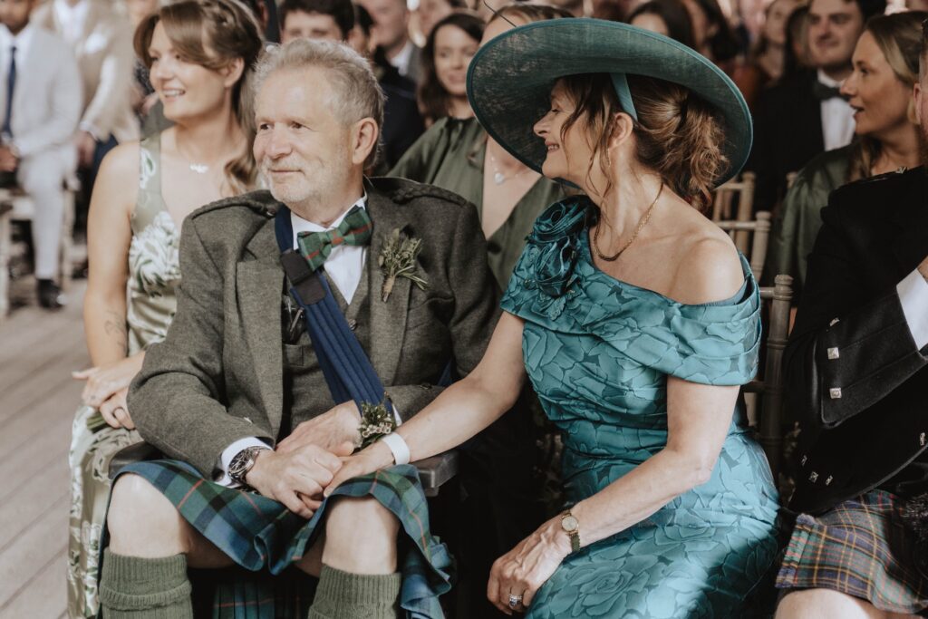The bride's parents holding hands as they watch their daughter get married during Dunglass Estate ceremony