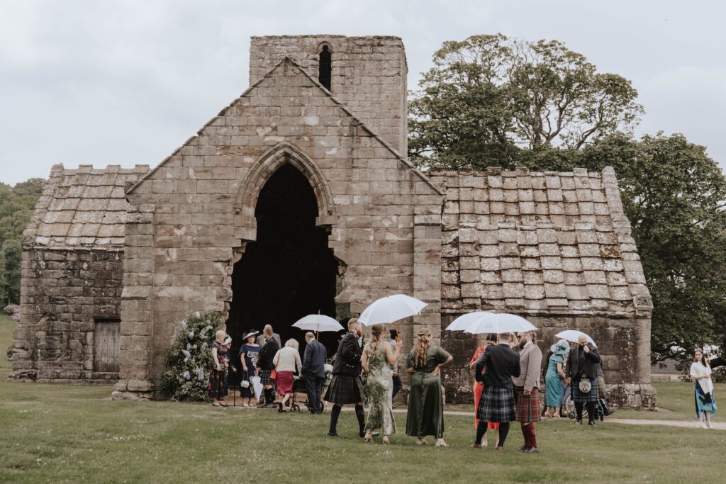 Guests with umbrellas up at Dungalss Estate during raining wedding
