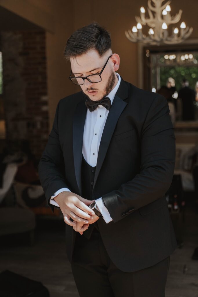 Groom adjusting his black tie before his wedding ceremony at Gaynes Park