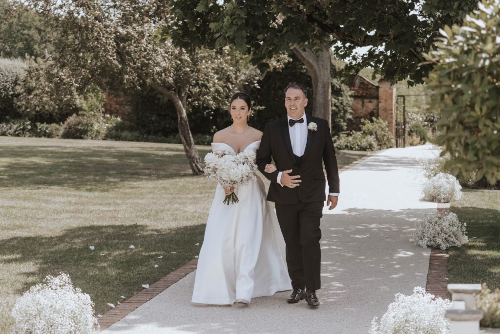 Abbie walking down the aisle with her father at Gaynes Park