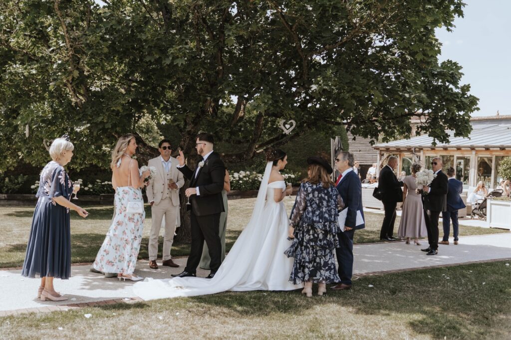 Wedding guests enjoying drinks in the gardens at Gaynes Park
