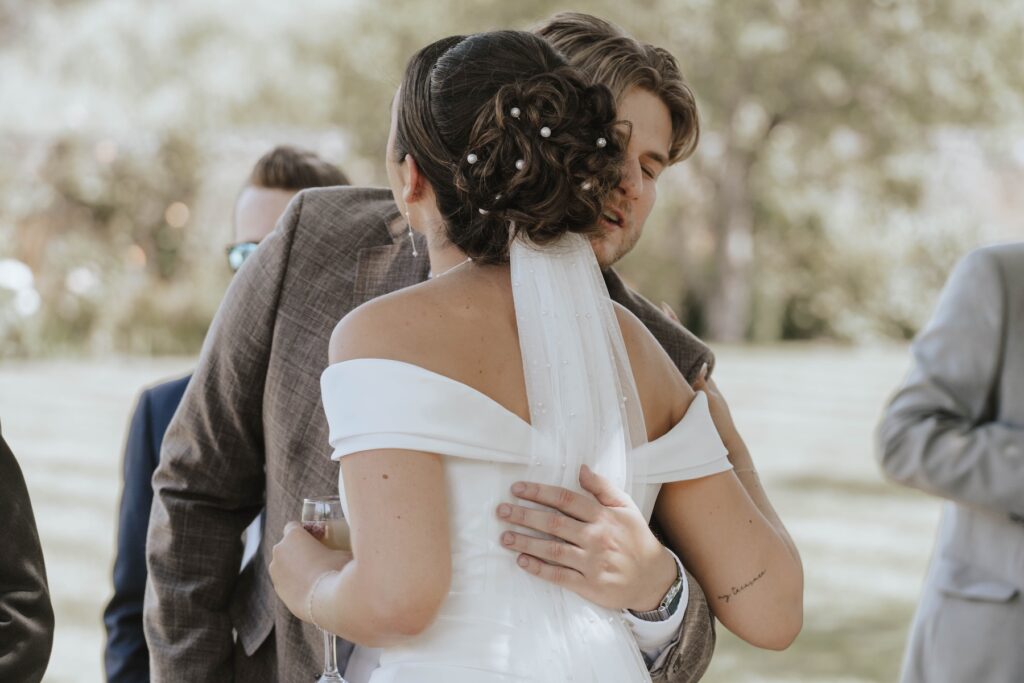 Candid wedding guests hugging during the drinks reception