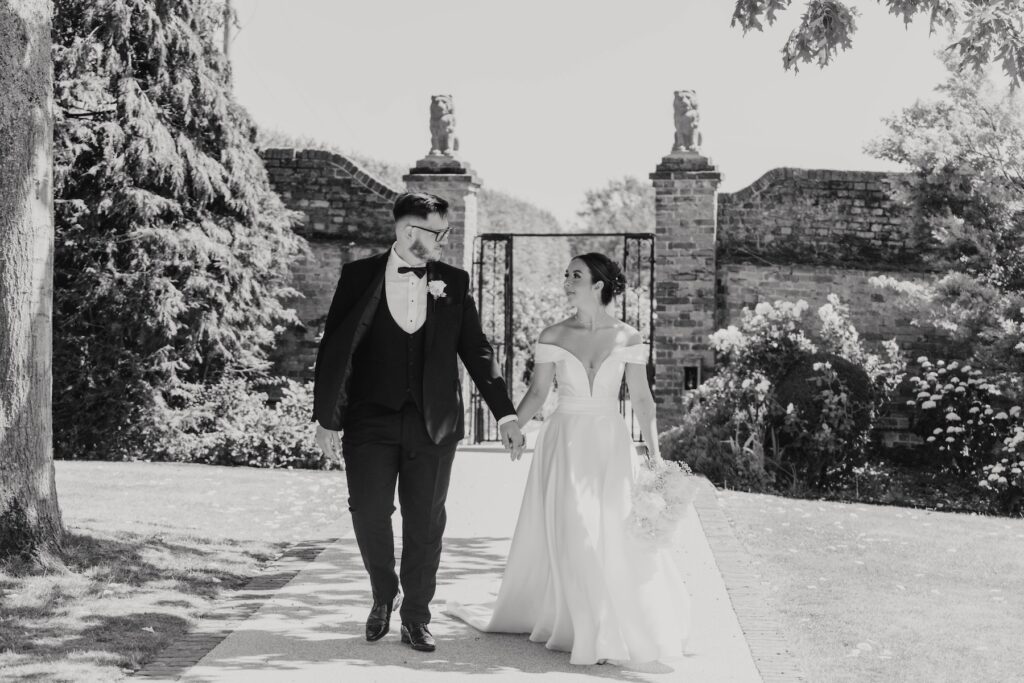 Bride and groom walking through the summer gardens at Gaynes Park
