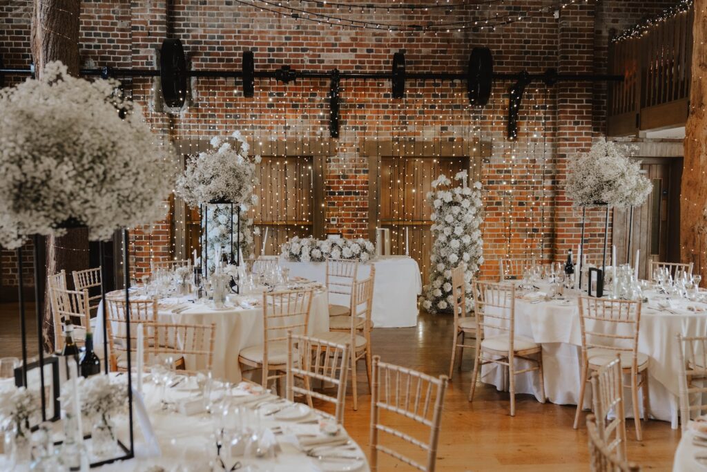 Wedding breakfast room decorated with white roses and fairy lights at Gaynes Park