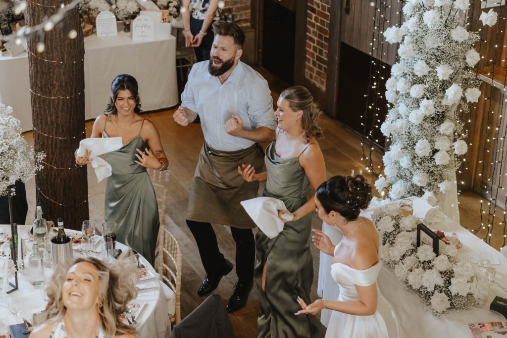 Wedding guests laughing during a surprise singing waiter performance