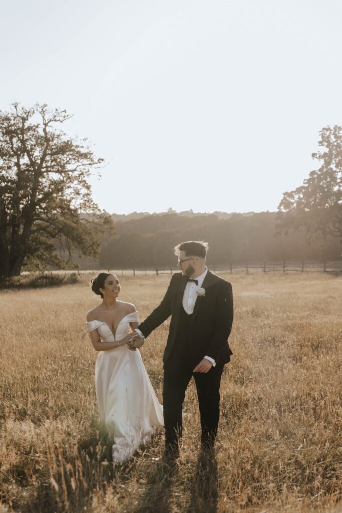 Newlyweds walking through long grass during golden hour in Essex
